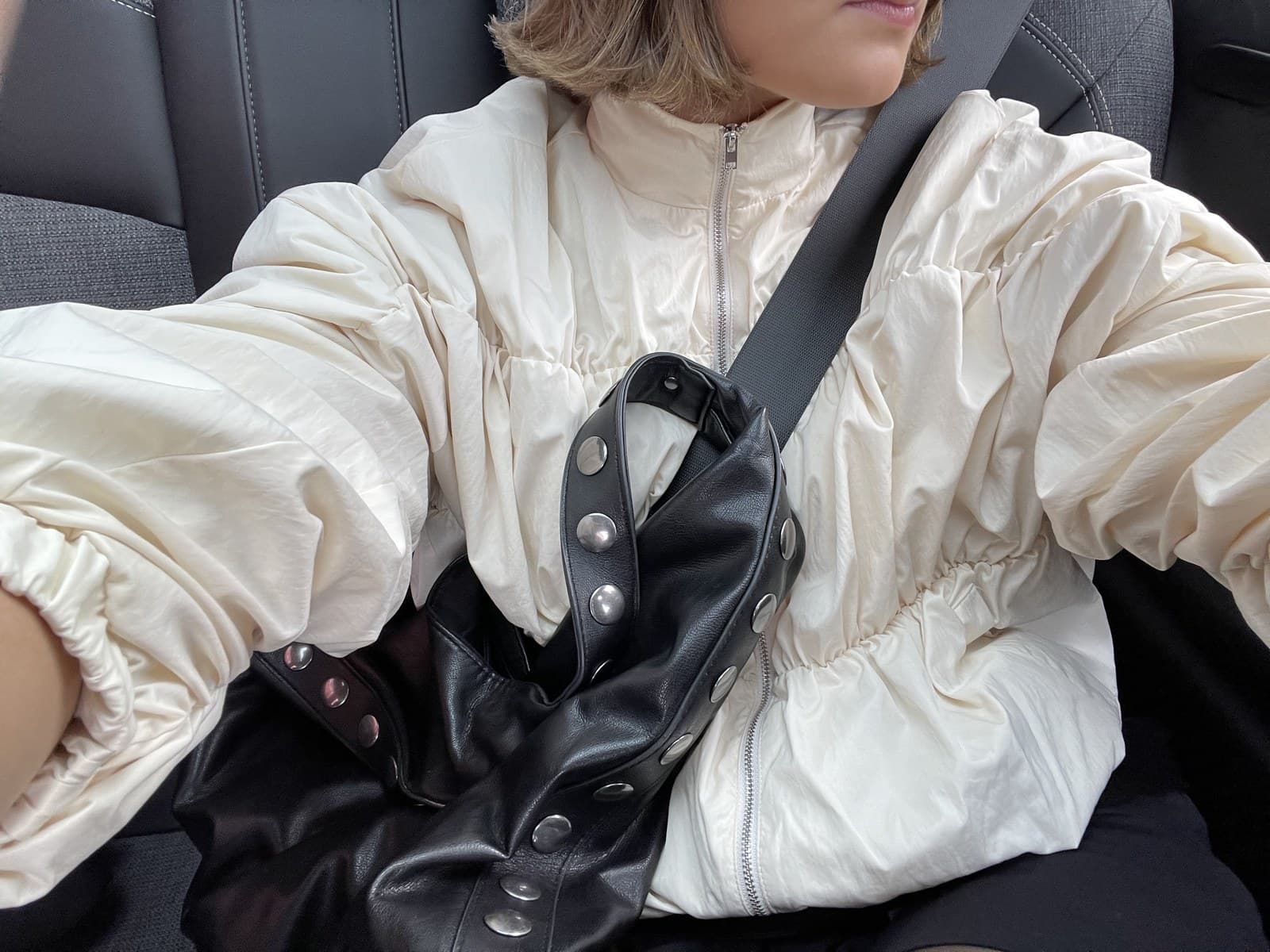 Eline in een crèmekleurige jas in de auto