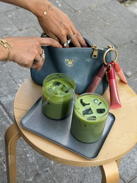 Twee iced matcha's naast een tas met lip tints